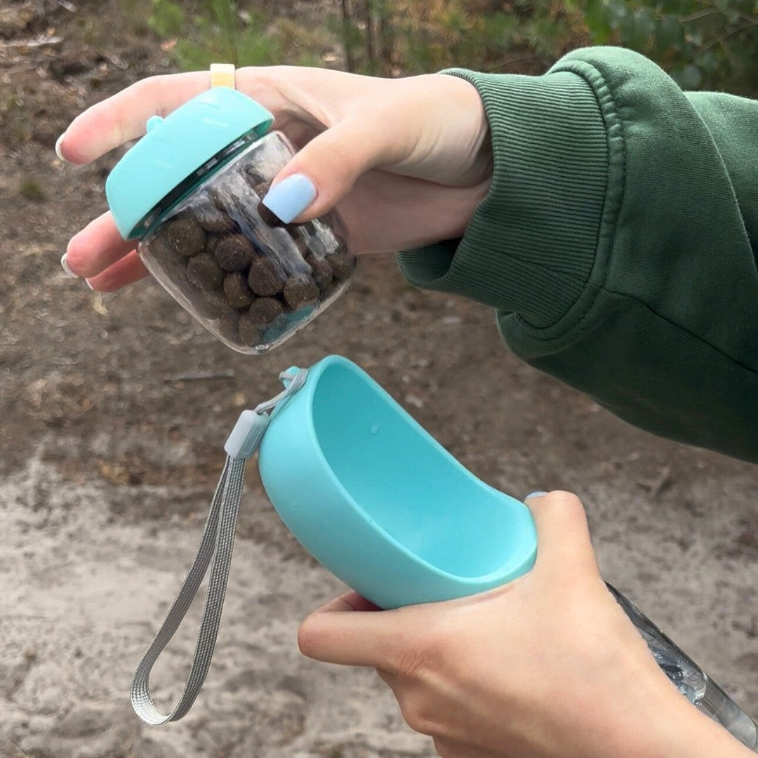 HydraBuddy drinkfles hond mintblauw — snackbakje met snacks en open drinkschaal in twee handen gehouden buiten