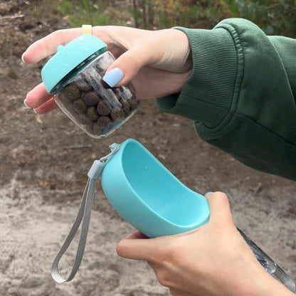 HydraBuddy drinkfles hond mintblauw — snackbakje met snacks en open drinkschaal in twee handen gehouden buiten