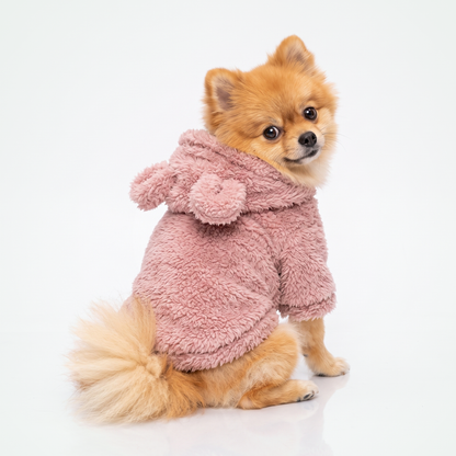Fleece hondentrui met capuchon in roze, met teddy-oortjes, gedragen door een pomeriaan die over haar schouder kijkt